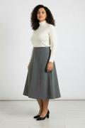 Woman wearing a white turtleneck and gray skirt against a white background